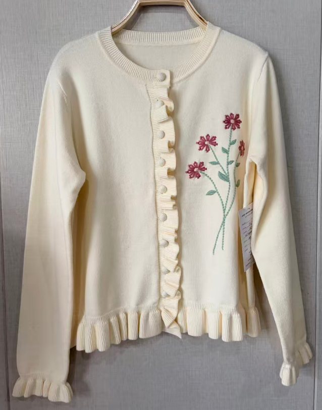 Ivory cardigan with ruffle placket and floral embroidery, style DS27-05060, from the Knitwear World sample collection